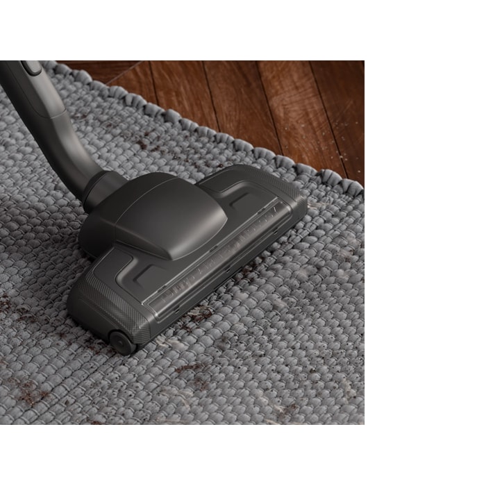Turbo floor nozzle vacuuming dirt of a grey carpet.