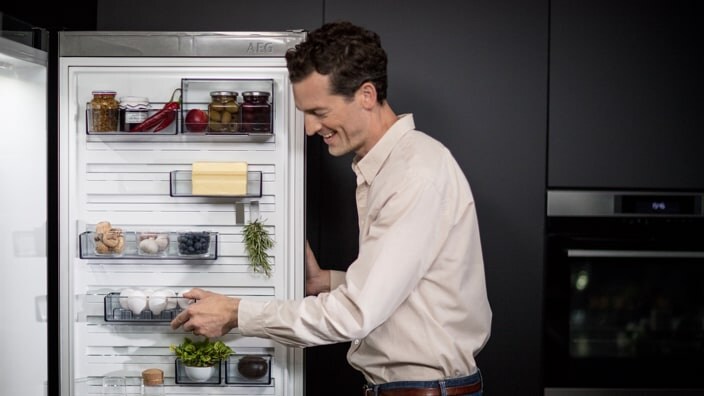 Home a arrumar alimentos no frigorífico