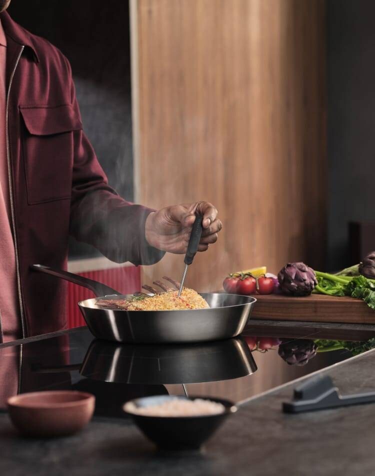 Uma pessoa a preparar comida numa placa de indução.