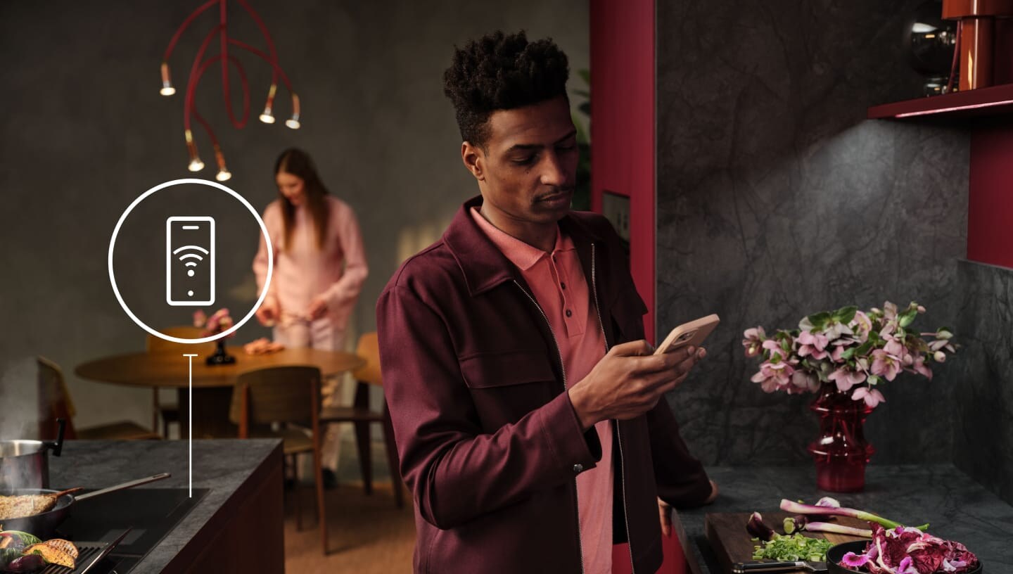 Um homem a olhar para o seu telefone na cozinha.