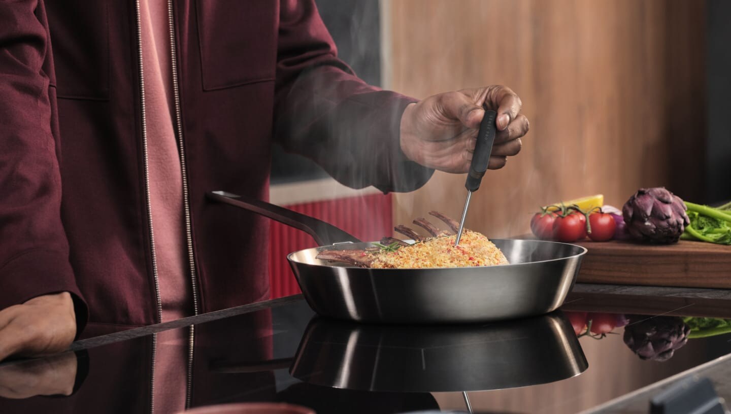 Uma pessoa a preparar comida numa placa de indução