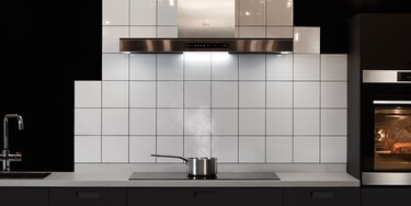 Salmão a ser cozinhado numa placa de indução enquanto o excesso de vapor é extraído pelo exaustor