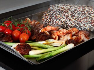Legumes e carne a fritar em conjunto num grelhador Teppanyaki da AEG.