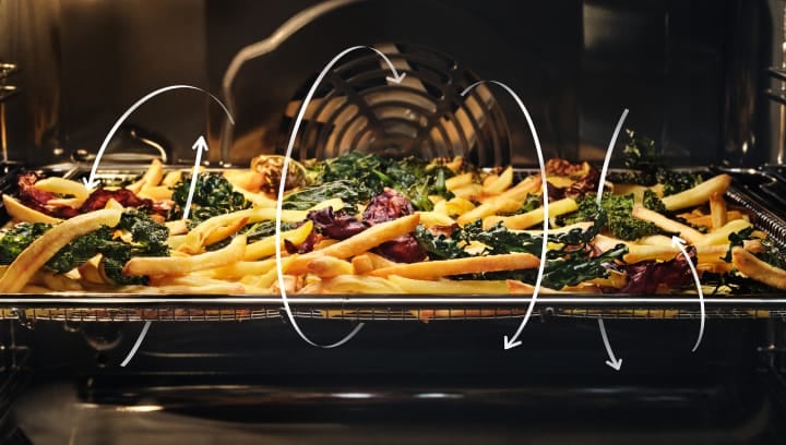 Batatas fritas e legumes a cozinhar no forno.