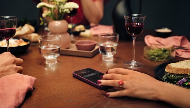 Pessoas sentadas à volta de uma mesa com comida e bebida.