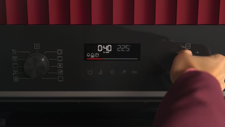 Uma pessoa a usar o painel de controlo de um forno.