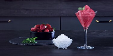 Daiquiri de morango ao lado de morangos e gelo