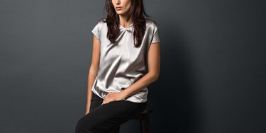 Mulher com uma blusa de seda prateada acabada de lavar