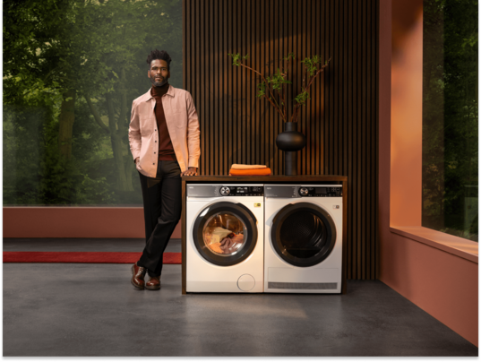 Man standing next to a washing machine unit.