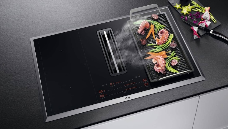 Comida a cozinhar numa grelha plancha colocada numa placa AEG.