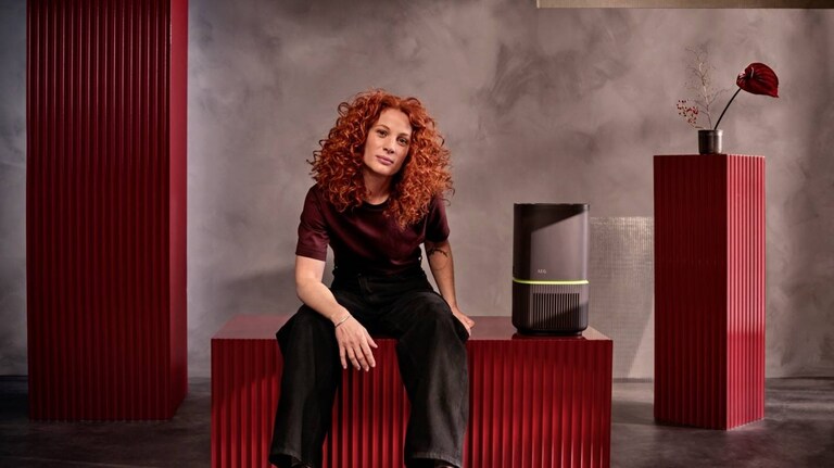 Uma mulher está sentada junto ao purificador de ar