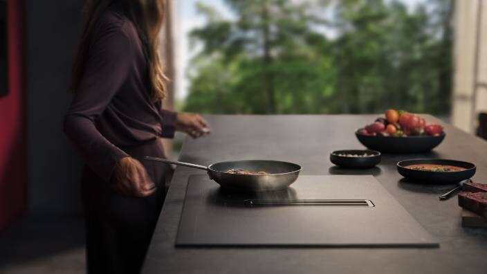 Uma senhora a cozinhar comida numa frigideira no AEG SaphirMatt®