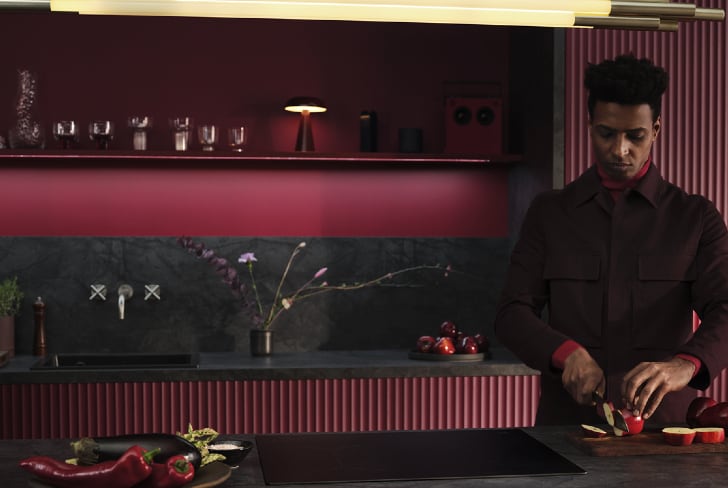 Um homem a cortar fruta na cozinha.